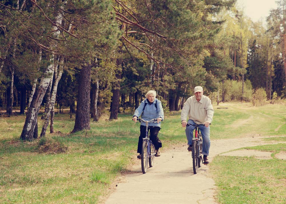 senior couple biking through wooded park